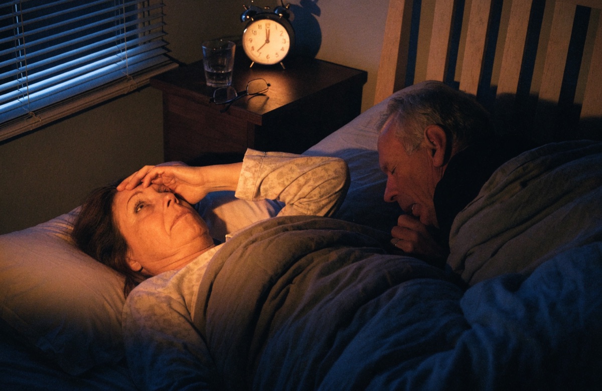 A woman lying awake at night beside her coughing husband
