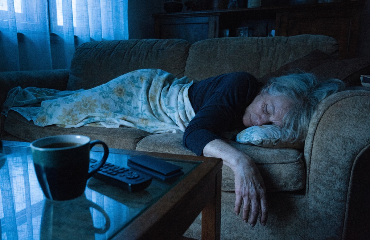 A woman asleep on the living room sofa before dawn