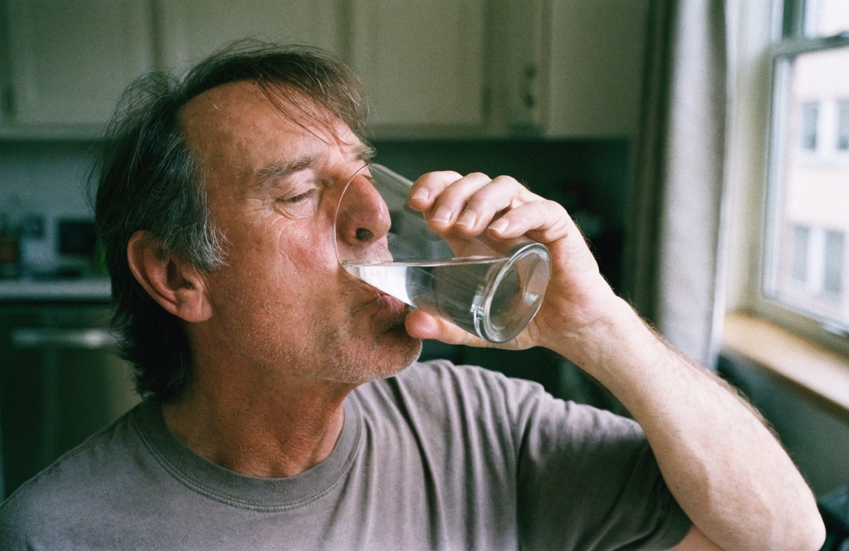 A man drinking a glass of water in his kitchen in the morning